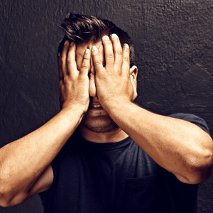 man in black t-shirt holding his hands to his face