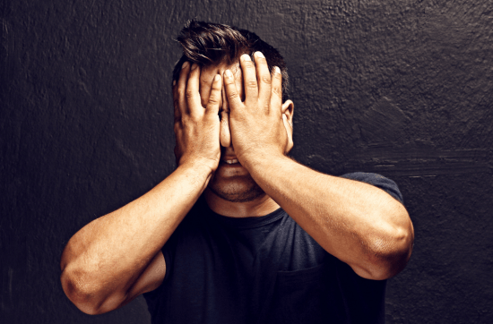 man in black t-shirt holding his hands to his face