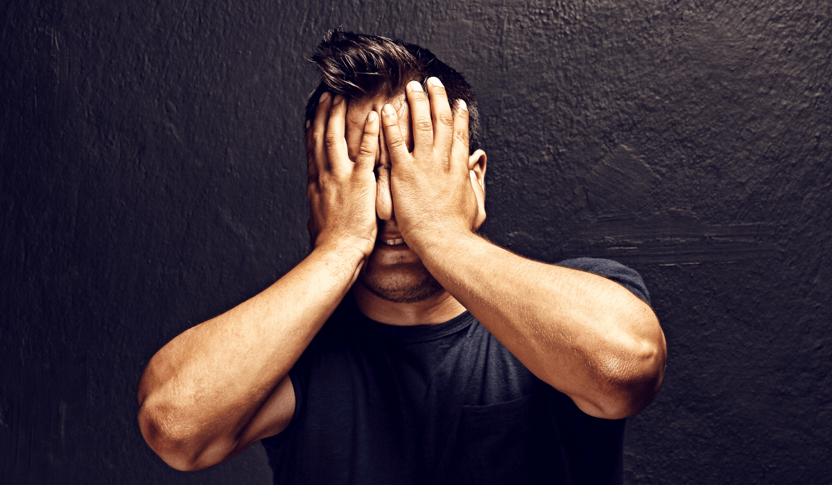 man in black t-shirt holding his hands to his face