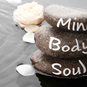 three pebbles lined up on a beach with words body, mind, soul written on it