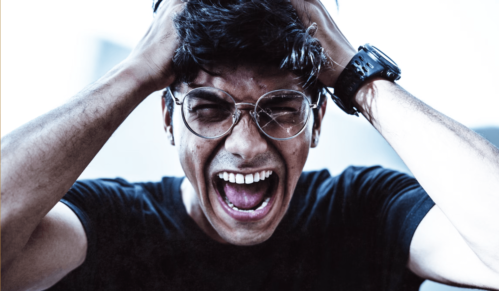 man wearing eyeglasses pulling his hair