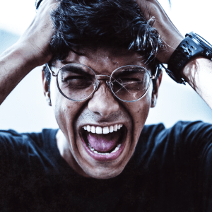 man wearing eyeglasses pulling his hair