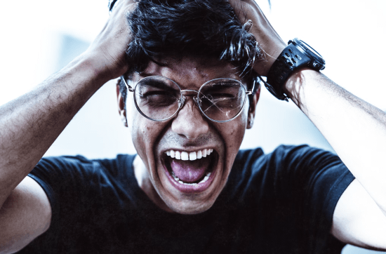 man wearing eyeglasses pulling his hair