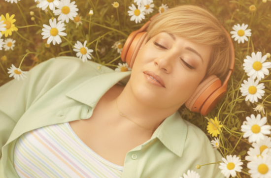 intuitive life mentor Sahar Huneidi Palmer lying on a bed of daisies wearing orange headphones