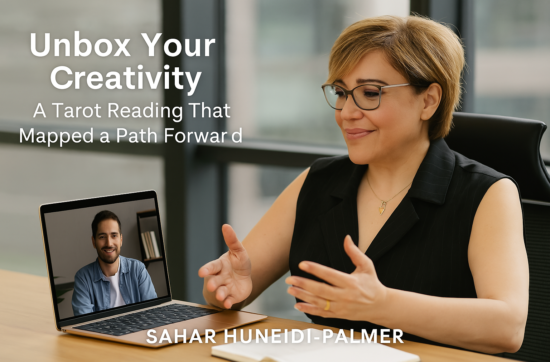 Sahar Huneidi-Palmer seated in a professional office space, leading a virtual Life Path Reading session via laptop, with natural light streaming through large windows and a smiling male client visible on the screen—illustrating the online Unbox Life Mentoring experience