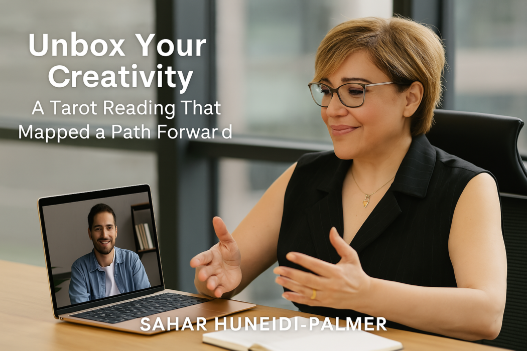 Sahar Huneidi-Palmer seated in a professional office space, leading a virtual Life Path Reading session via laptop, with natural light streaming through large windows and a smiling male client visible on the screen—illustrating the online Unbox Life Mentoring experience