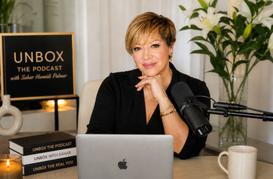 Sahar Huneidi Palmer recording Unbox The Podcast with microphone and laptop, focused on alignment and clarity